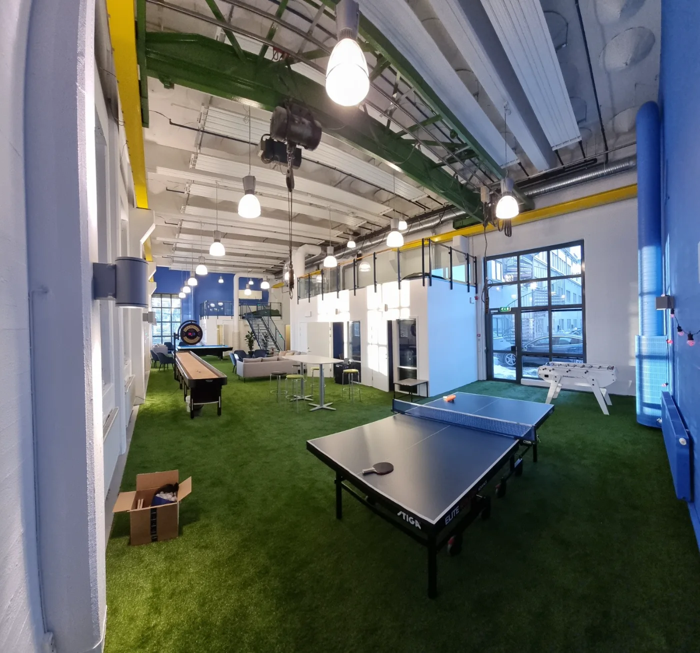 Mesa de ping-pong e pebolim junto à entrada envidraçada