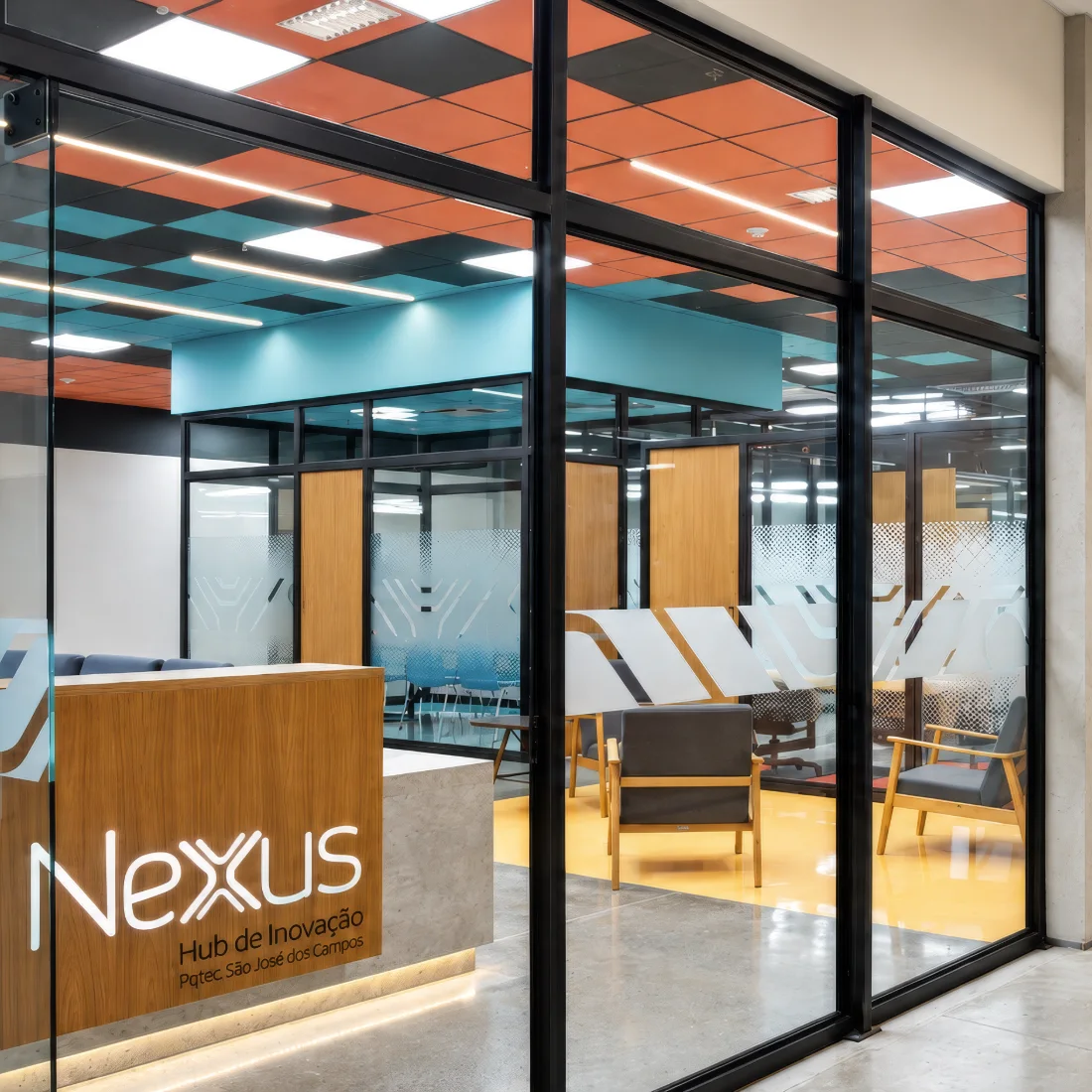 Coworking Júpiter: convivência central sob forro em xadrez colorido, entre salas envidraçadas