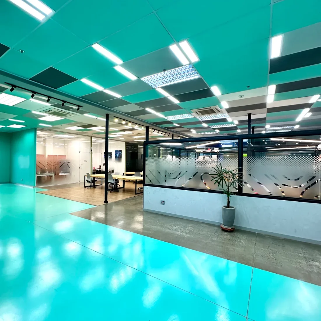 Coworking Urano: salão com forro em xadrez turquesa e faixa de piso conduzindo às estações