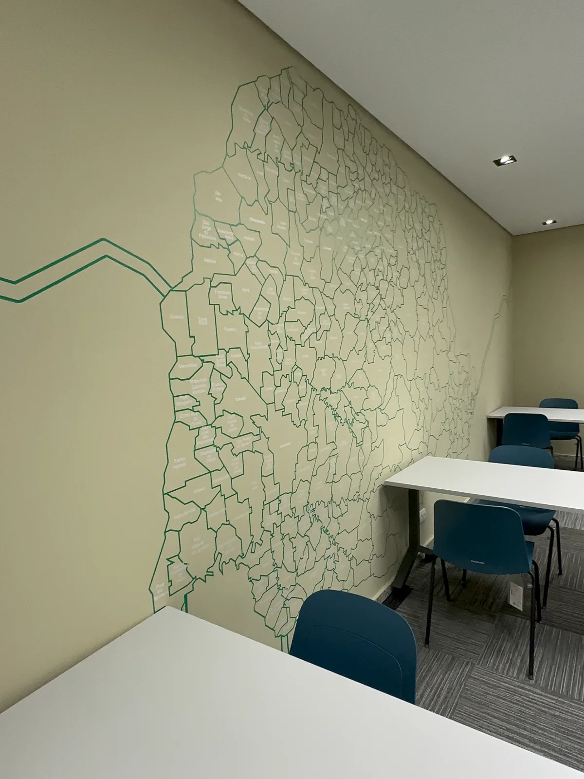 Mapa dos municípios do Paraná traçado em verde na parede da sala de treinamento
