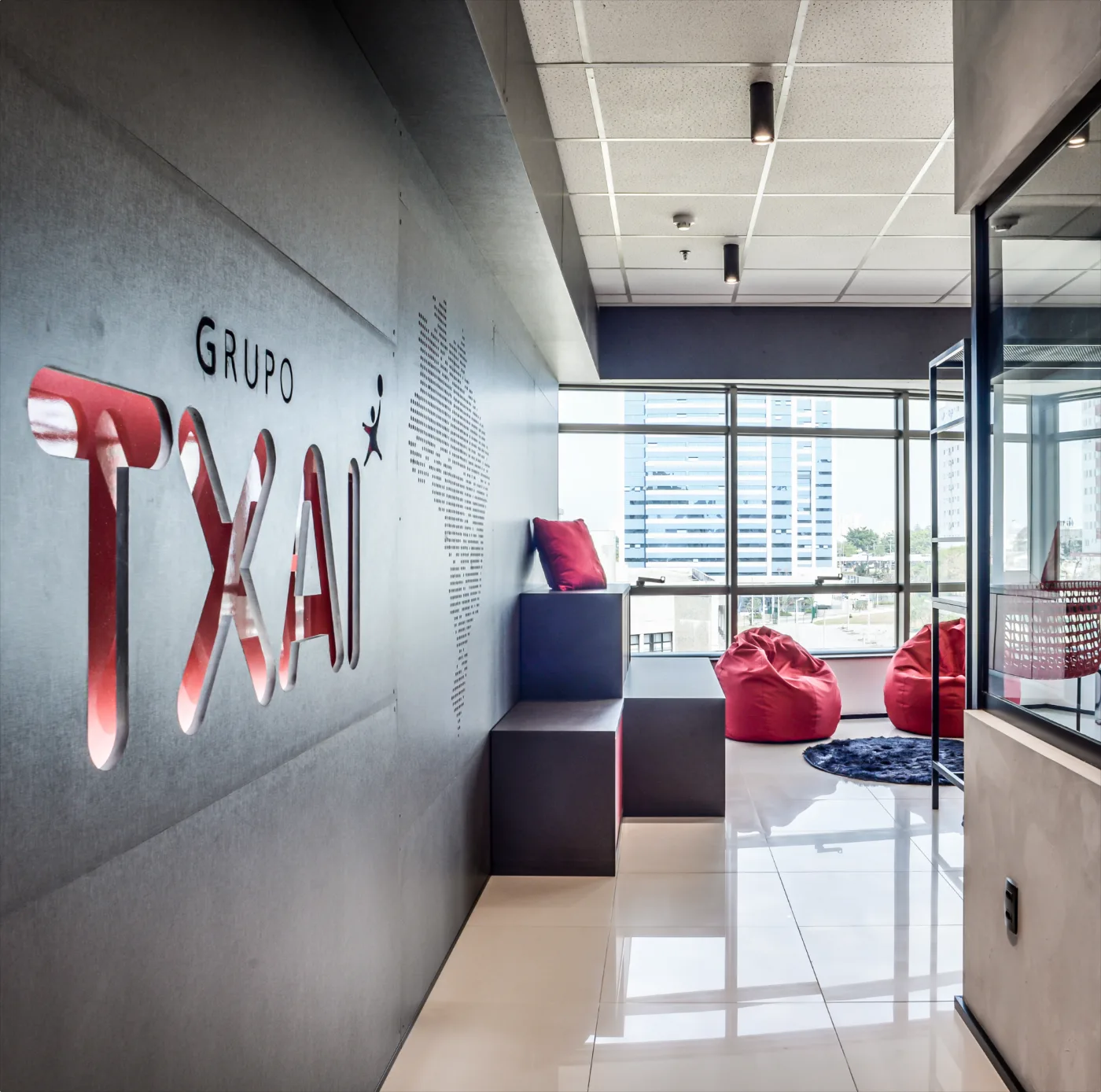 Grupo Txai: área de convivência junto à fachada envidraçada, com marca em relevo na parede de concreto