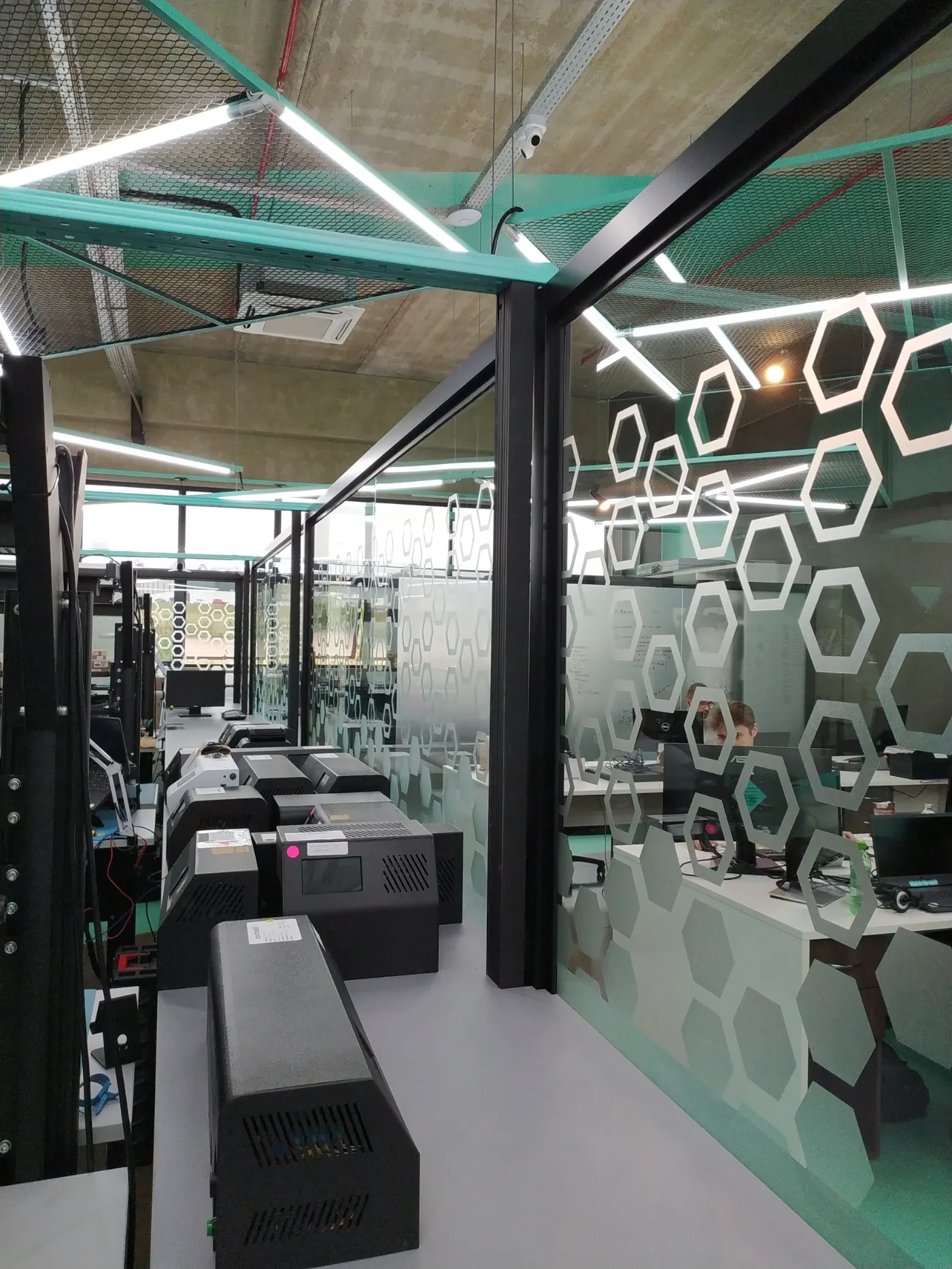 Bancadas de laboratório com equipamentos alinhados e vedação em vidro com grafismo hexagonal