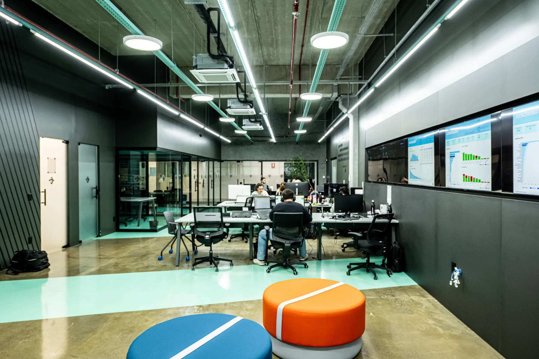 Open space de operação do CIT-R, com estações de trabalho, painel de monitores e piso verde-água delimitando a circulação