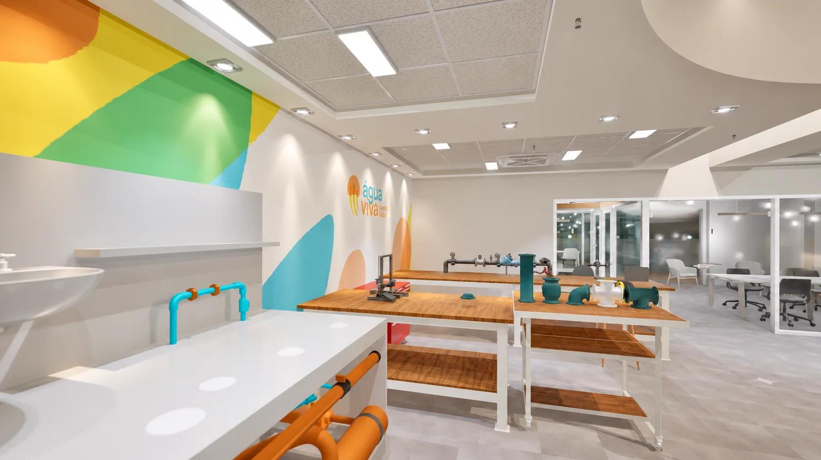 Laboratório de prototipagem, com bancadas de madeira, peças hidráulicas, bancada técnica com pia e grafismo colorido da marca Água Viva