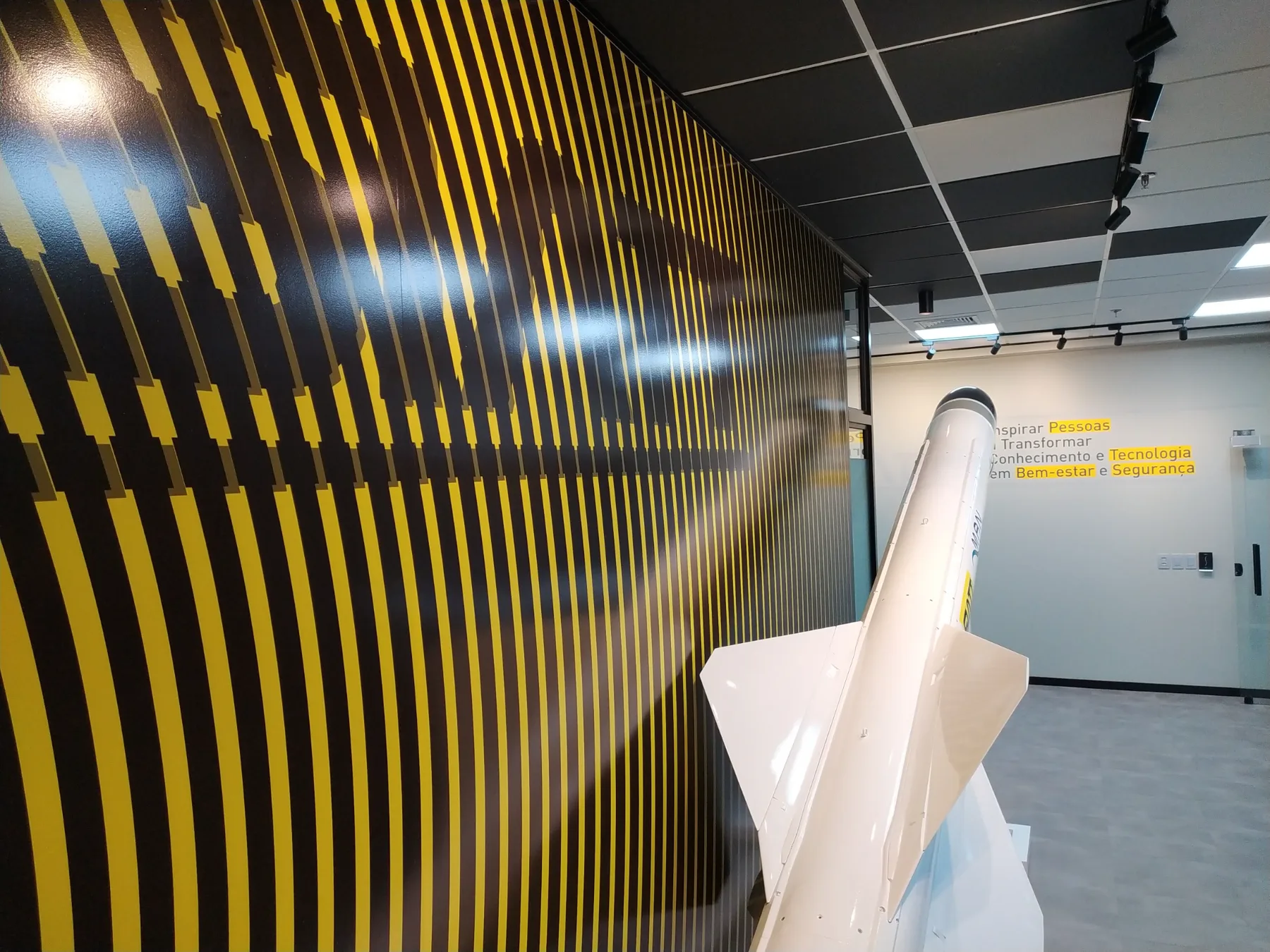 Parede de grafismo amarelo e preto do showroom, com o manifesto da empresa aplicado na parede ao fundo